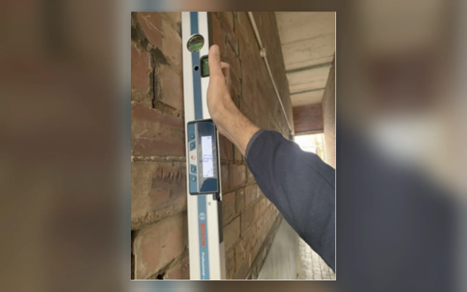 Structural engineer checking wall alignment with a digital level